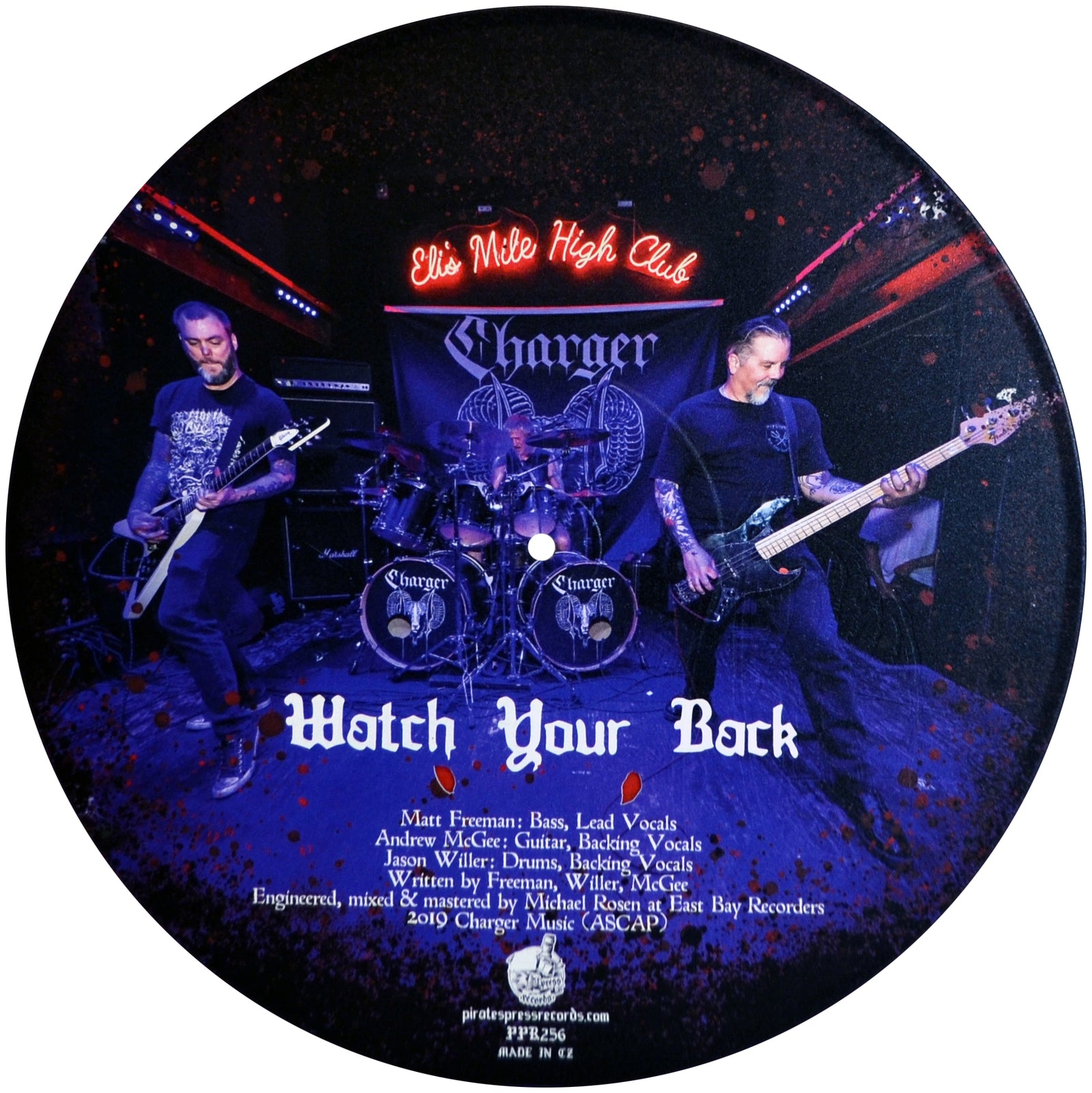 A round punk metal vinyl from Charger features a live band photo, with text listing members, song credits, and “Watch Your Back” in bold white letters at the bottom.