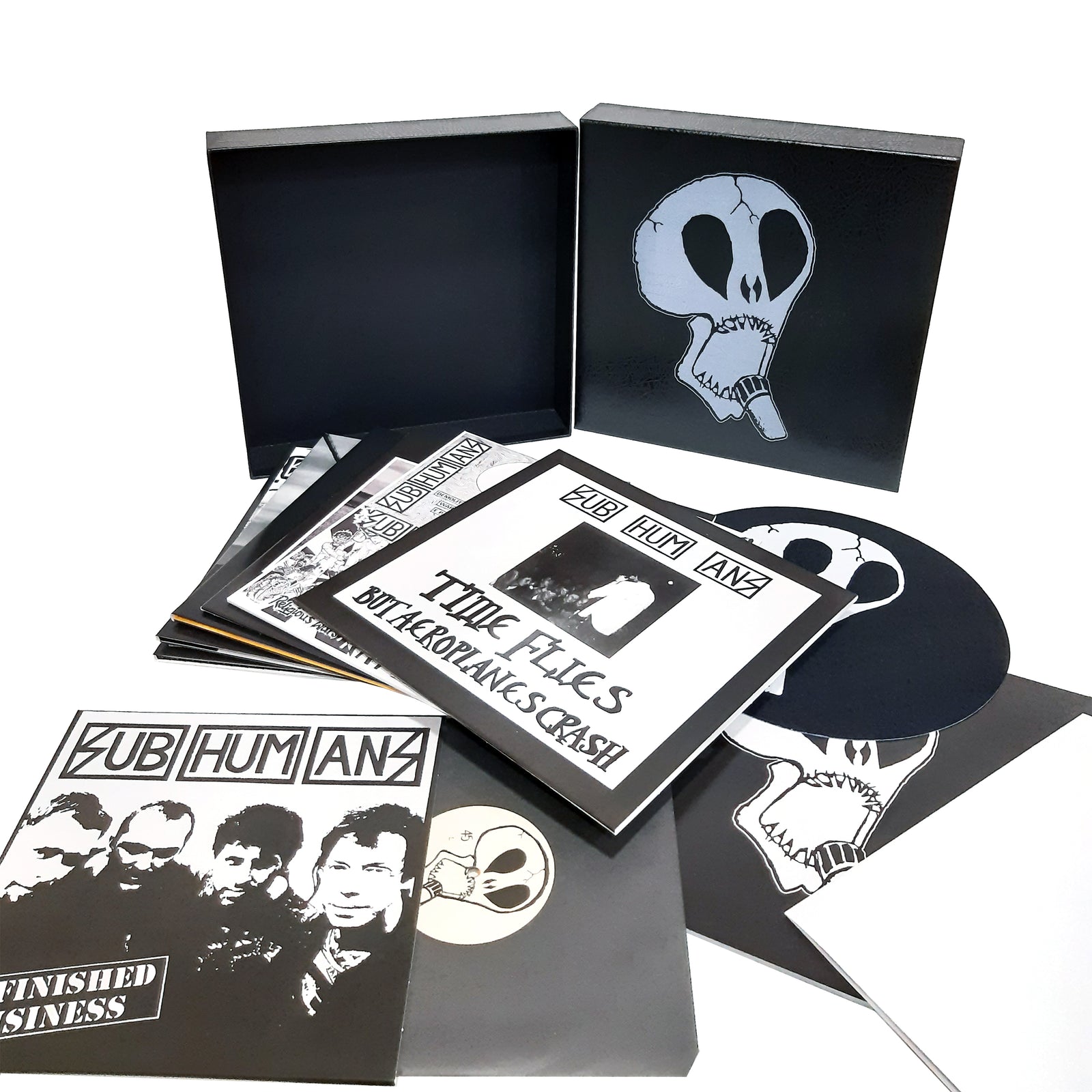 The Subhumans box set features anarcho punk albums with black and white artwork, skull illustrations, band photos, several record sleeves, vinyl records, and a black box with a large skull design. Brand: Subhumans.
