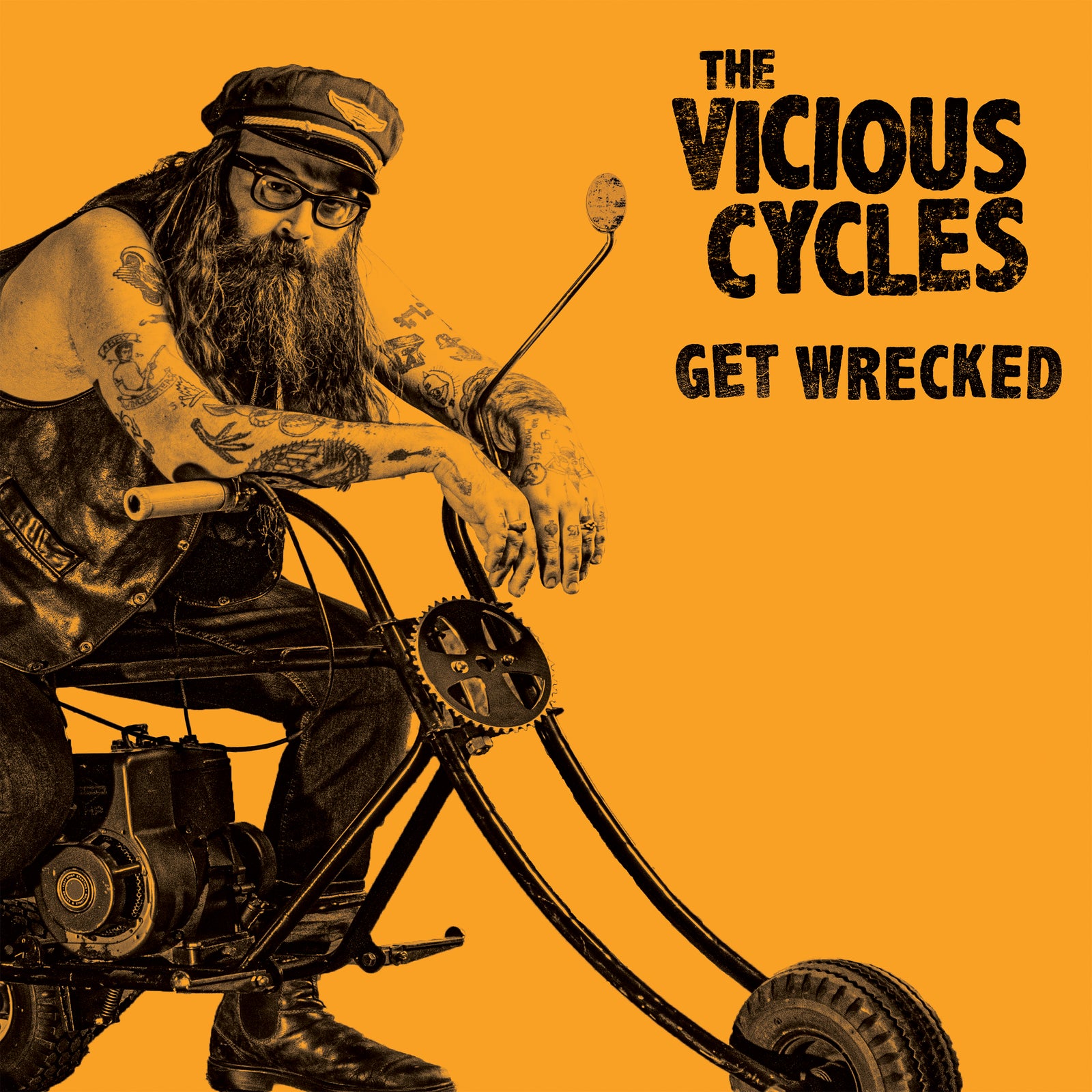 A bearded, tattooed person with glasses and a biker cap sits on a chopper motorcycle against an orange background. Text: The Vicious Cycles—garage punk rock and motorcycle party music vibes.