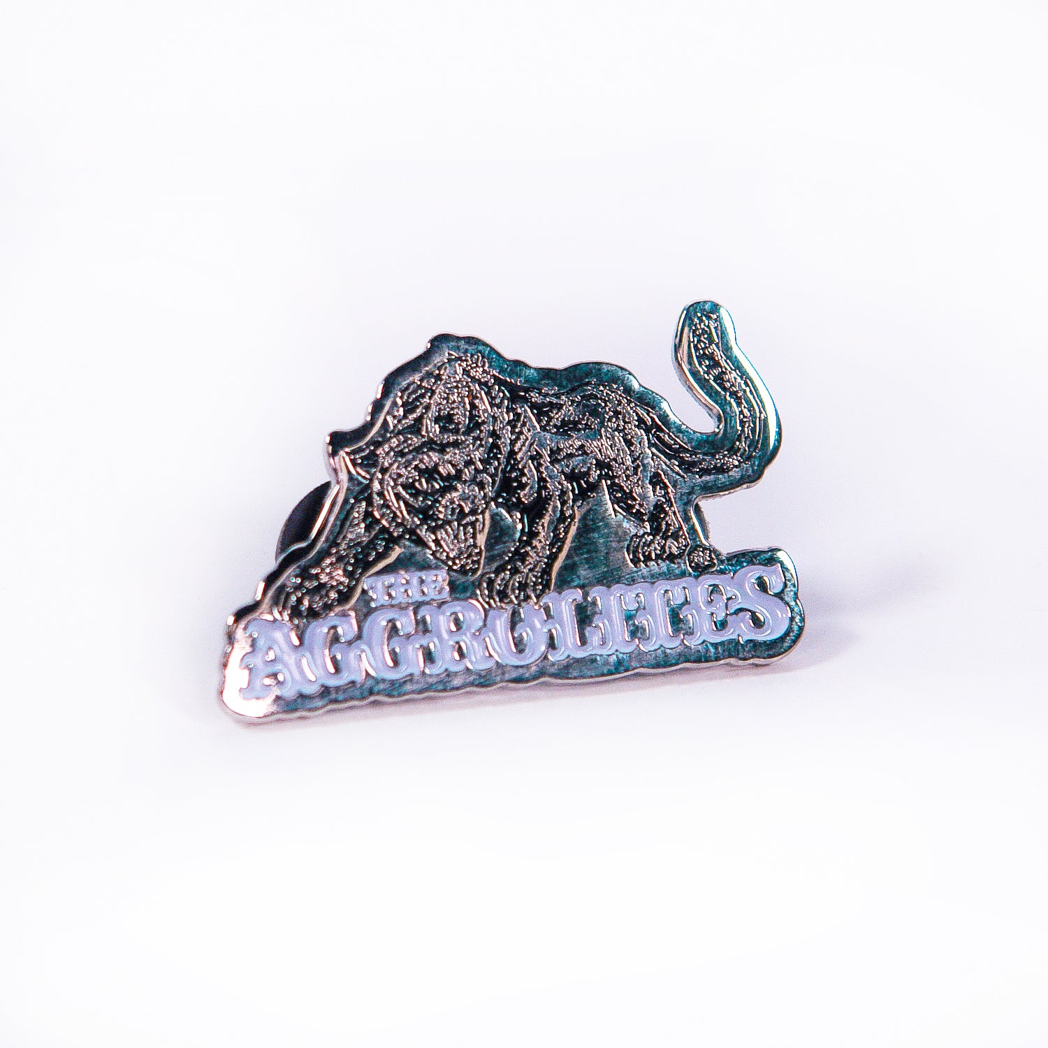 A metallic enamel pin by The Aggrolites features an illustrated tiger, the Aggropanther, standing over stylized, raised letters spelling THE AGGROLITES, displayed on a white background.