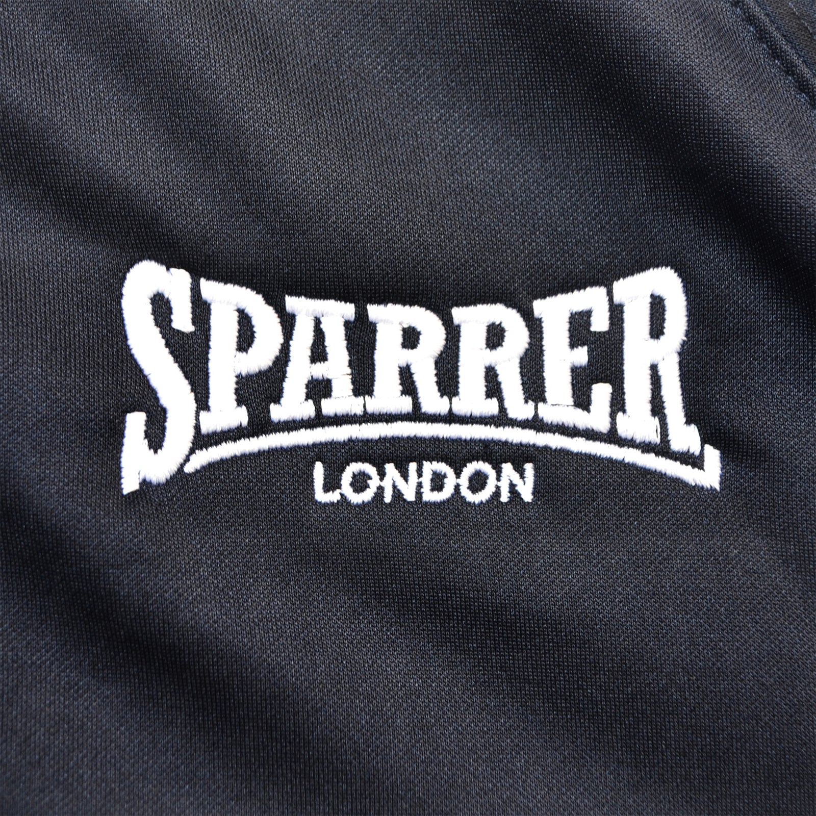 Black fabric with white embroidered SPARRER in large letters and LONDON beneath, inspired by the iconic Cock Sparrer track jacket from independent brand Cock Sparrer.