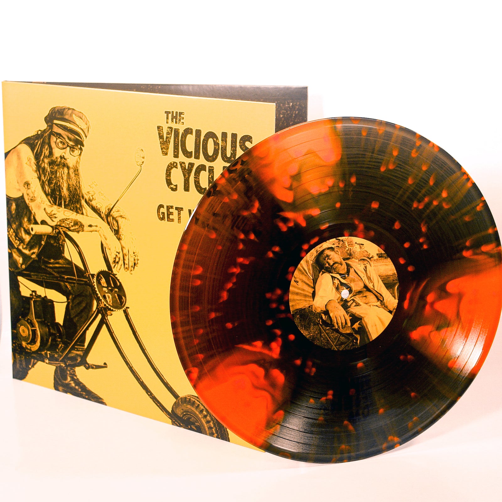 A striking orange and black splatter vinyl by The Vicious Cycles sits before its album cover, which shows a bearded man on a chopper with the text Get Rich or Try Dying—a must-have garage punk rock LP.