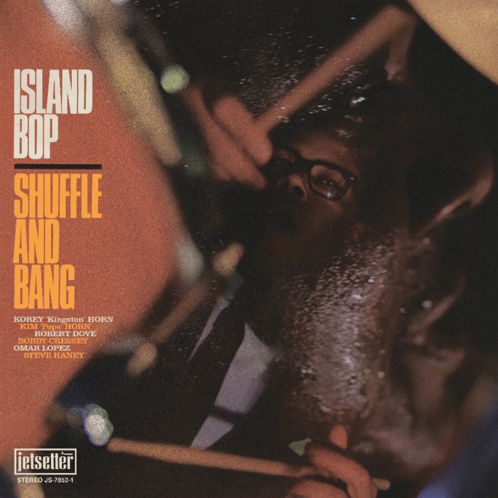 Album cover for Shuffle and Bang's Island Bop, capturing San Diego vibes with dub/reggae, features a close-up drummer in glasses, drumsticks blurred in action, and album text on the left over a dark reflective background.