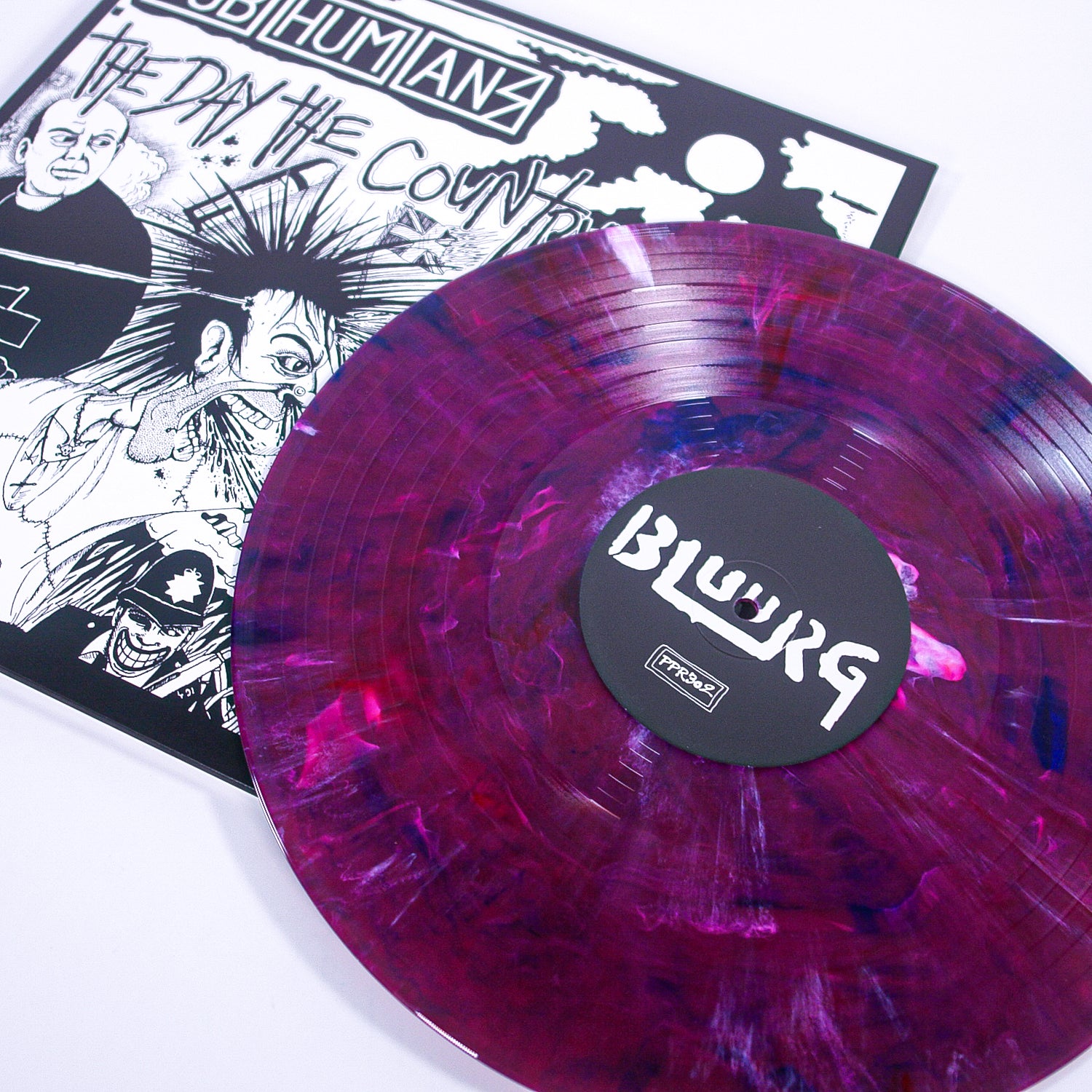 A marbled purple and pink Bluurg vinyl record sits on a black-and-white cover for The Day The Country Died by Subhumans.