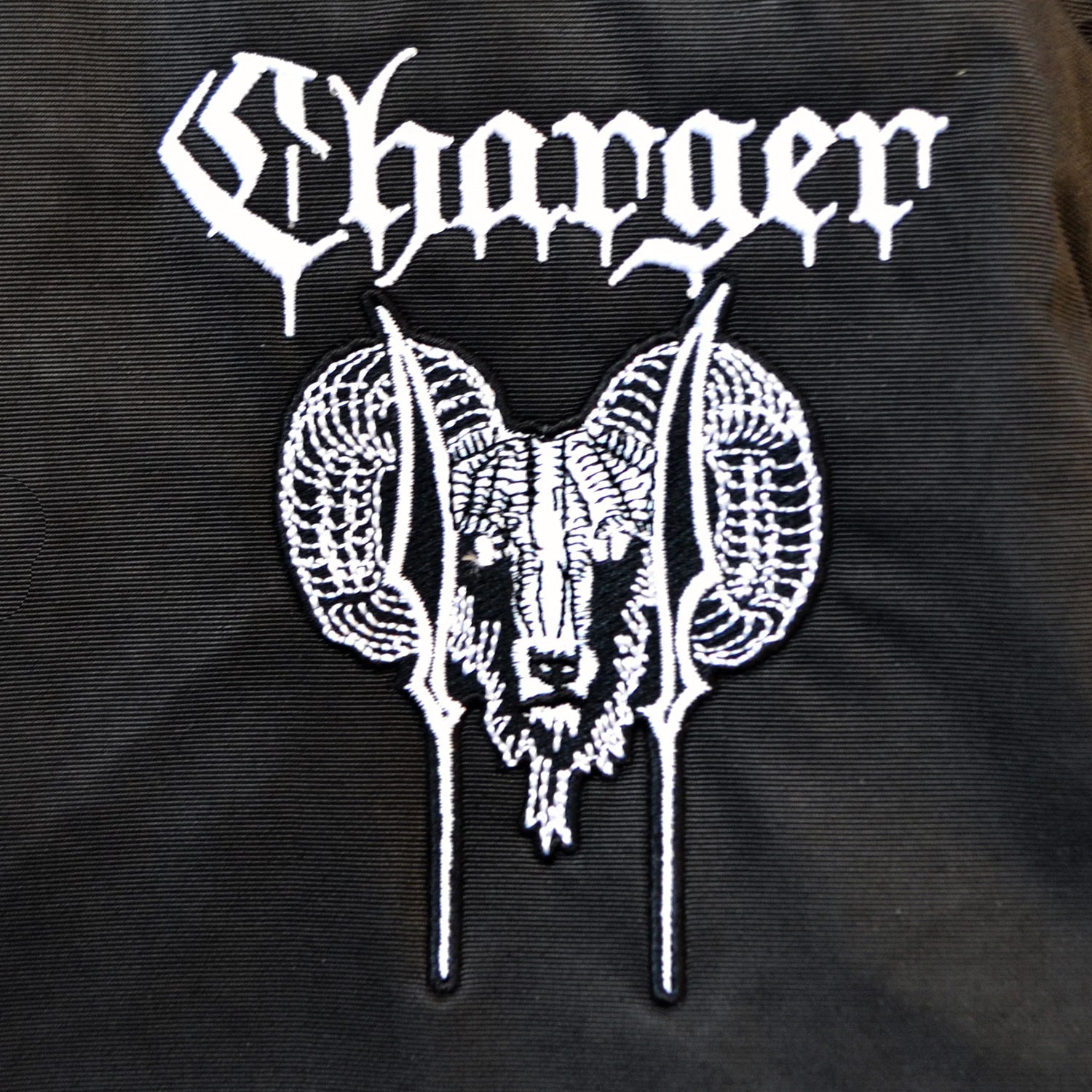 White stylized Charger text above an embroidered ram’s head with curled horns stands out on black fabric in this bold, gothic design featured on the Charger windbreaker weatherproof hooded anorak.