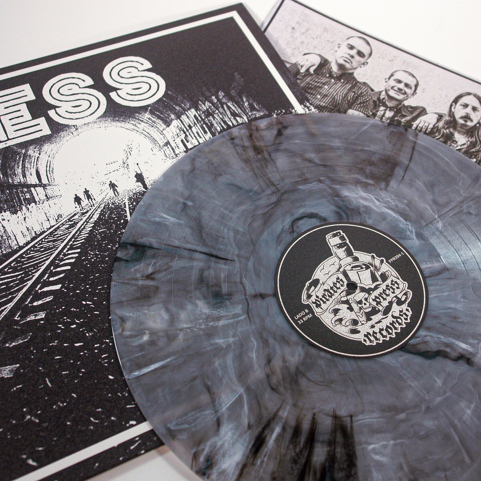A Ghost Marble Vinyl LP from Mess features a skull-labeled record on a black-and-white cover with a tunnel, train tracks, and silhouettes. A band photo insert peeks out—an ideal collectible for any Mess enthusiast.