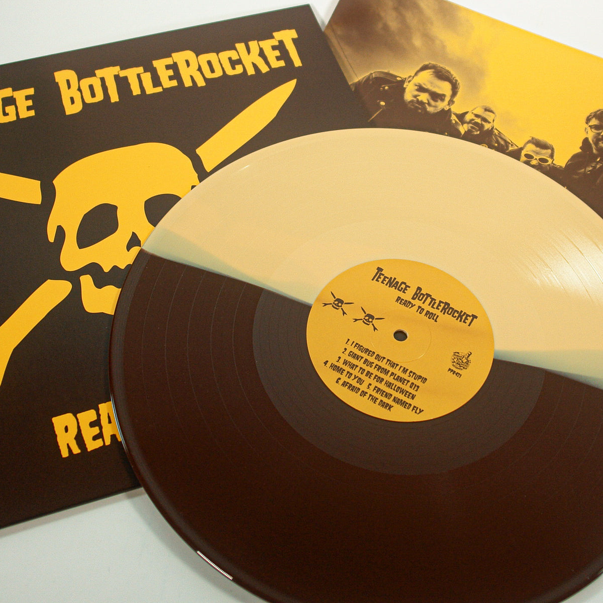 A Teenage Bottlerocket vinyl from Pirates Press Records, in half tan and half brown, rests on its album cover featuring a yellow skull and crossbones. Behind it, the sleeve shows band members in yellow with bold "Ready to Roll" text.
