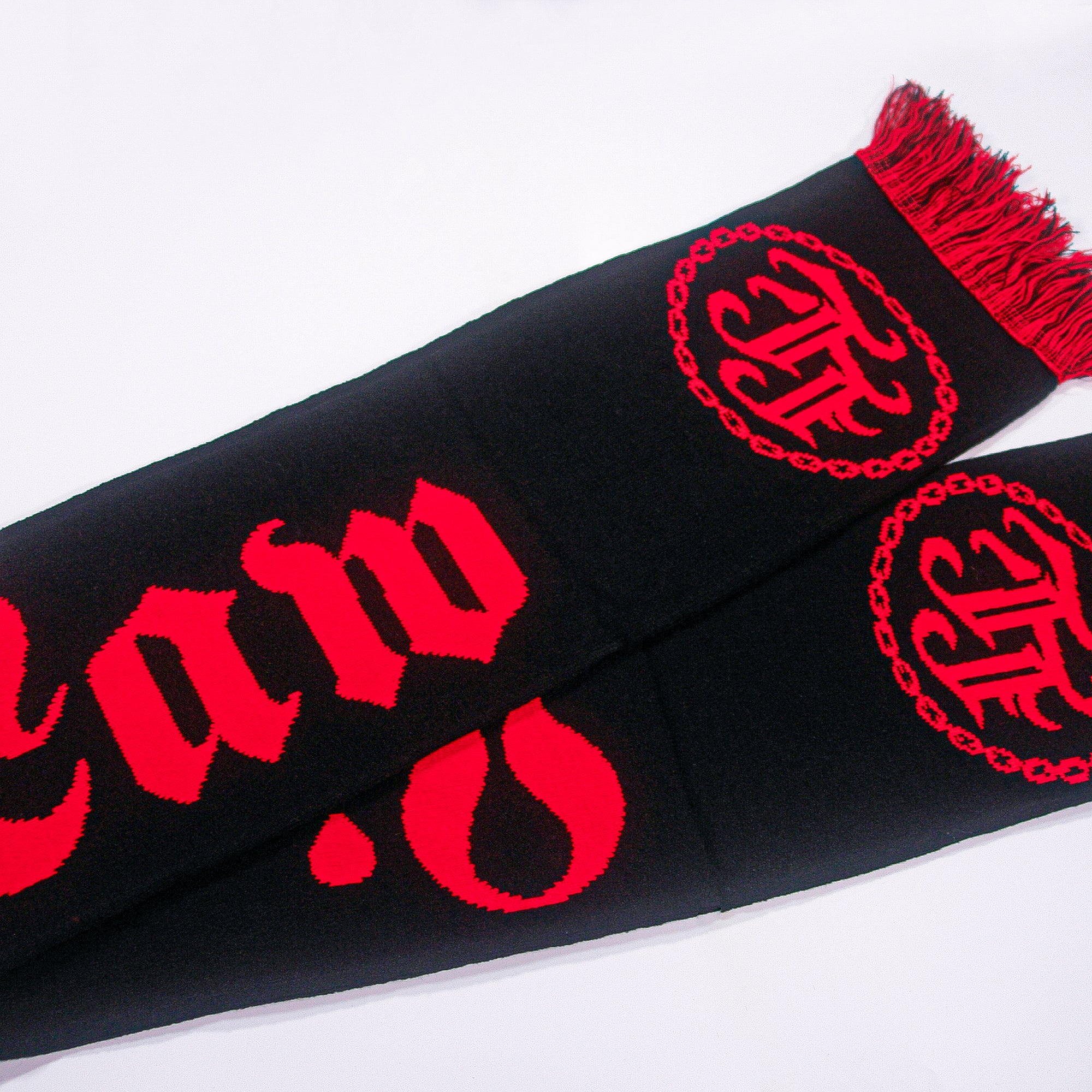 A bold black scarf by Lion's Law featuring their logo in red Gothic-style text and circular emblems, plus decorative fringes at one end—an eye-catching band accessory shown on a white background.
