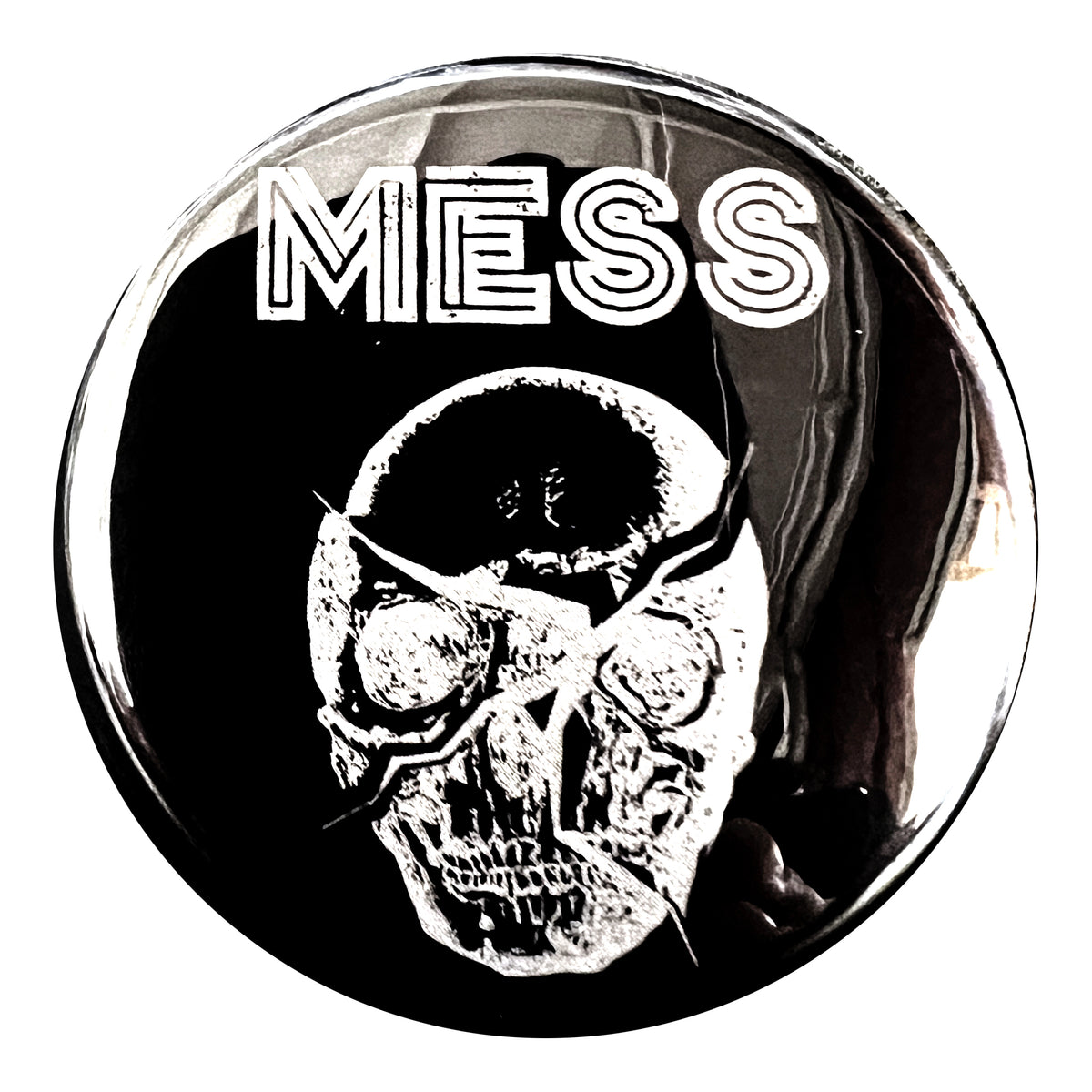 A round black Mess button featuring a distressed cracked white skull logo with bold white &quot;MESS&quot; lettering above it. The design has a grunge, edgy vibe.