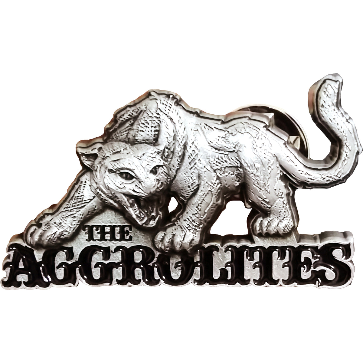 A silver enamel pin from The Aggrolites featuring a snarling big cat crouched above “THE AGGROLITES,” with a 3D print accentuating its open mouth and outstretched paw.
