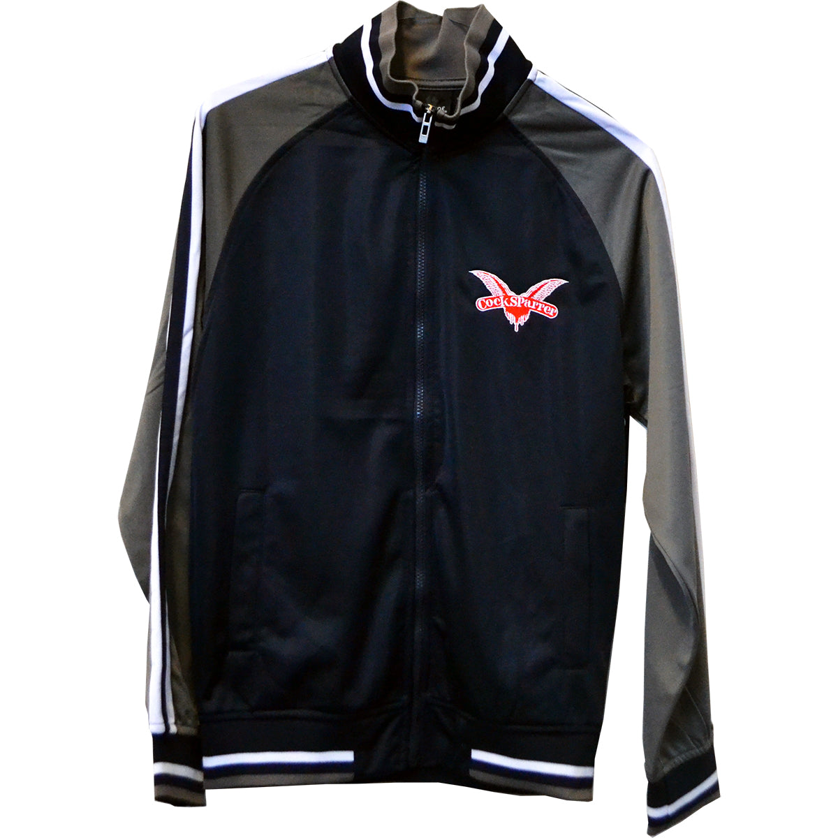 A black and gray Cock Sparrer zip track jacket with white sleeve stripes, red and white eagle logo inspired by Cock Sparrer Wings, and HACK SAW JIM DUGGAN text on the left chest.
