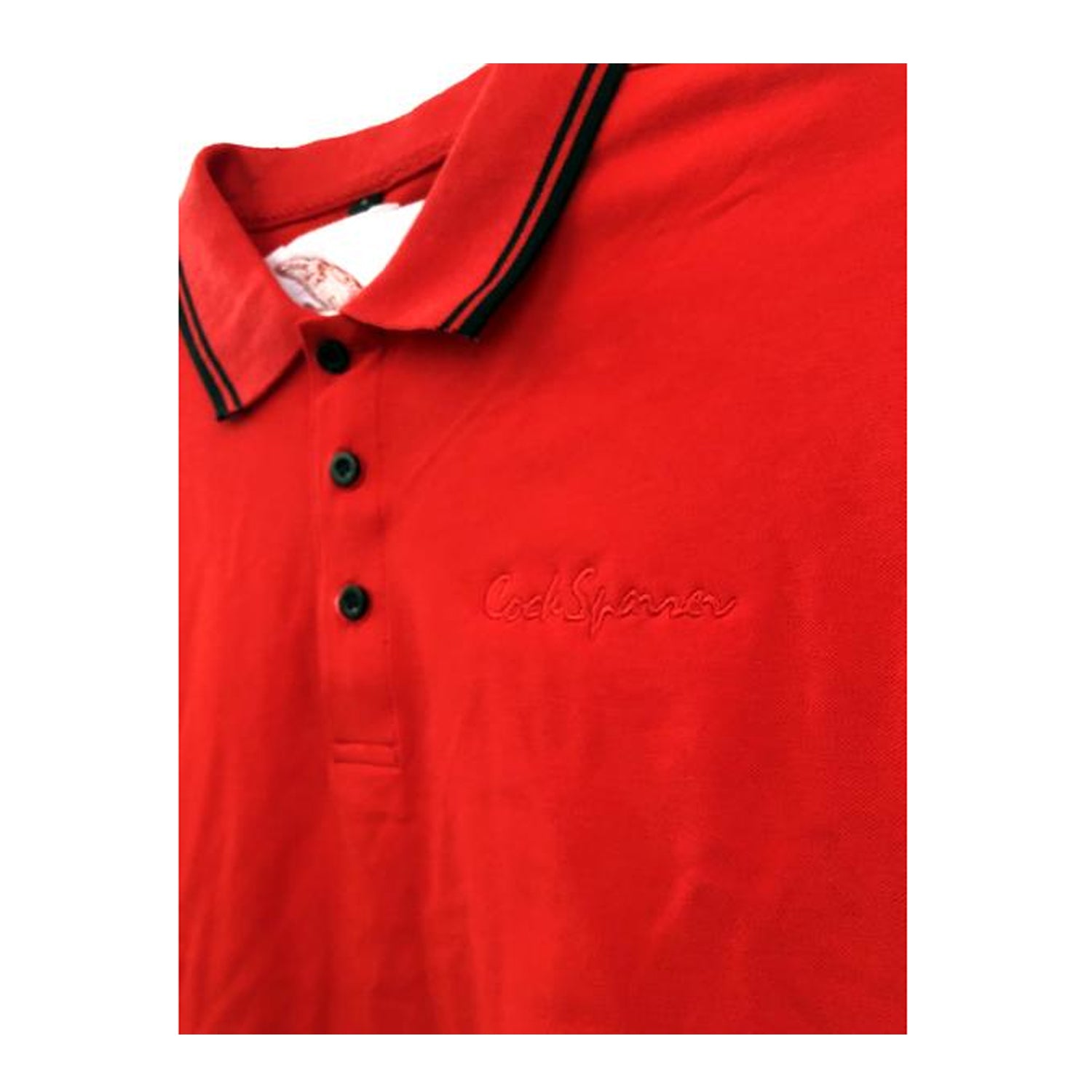 A bright red Cock Sparrer polo shirt with a collar, three black buttons, and black-striped trim on the collar and sleeves. The chest features a subtly embroidered Cock Sparrer logo in matching red thread.