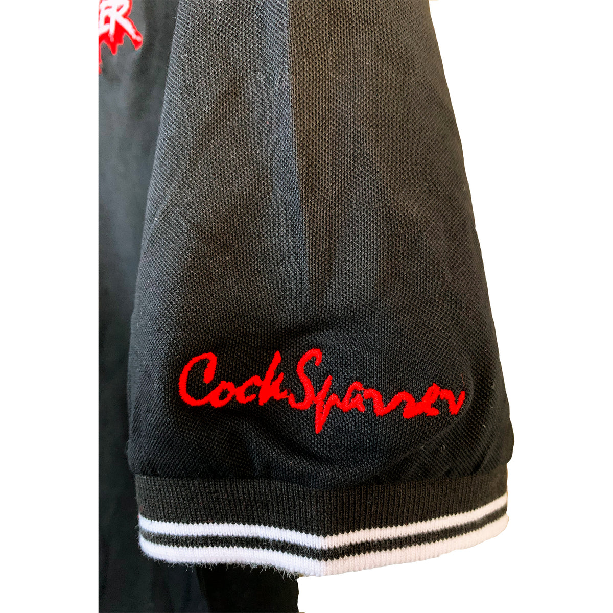 A black jacket sleeve with a white-striped cuff and Cock Sparrer embroidered in bright red cursive is perfect for fans of the Cock Sparrer brand or anyone who appreciates classic polo and embroidered crest styles.
