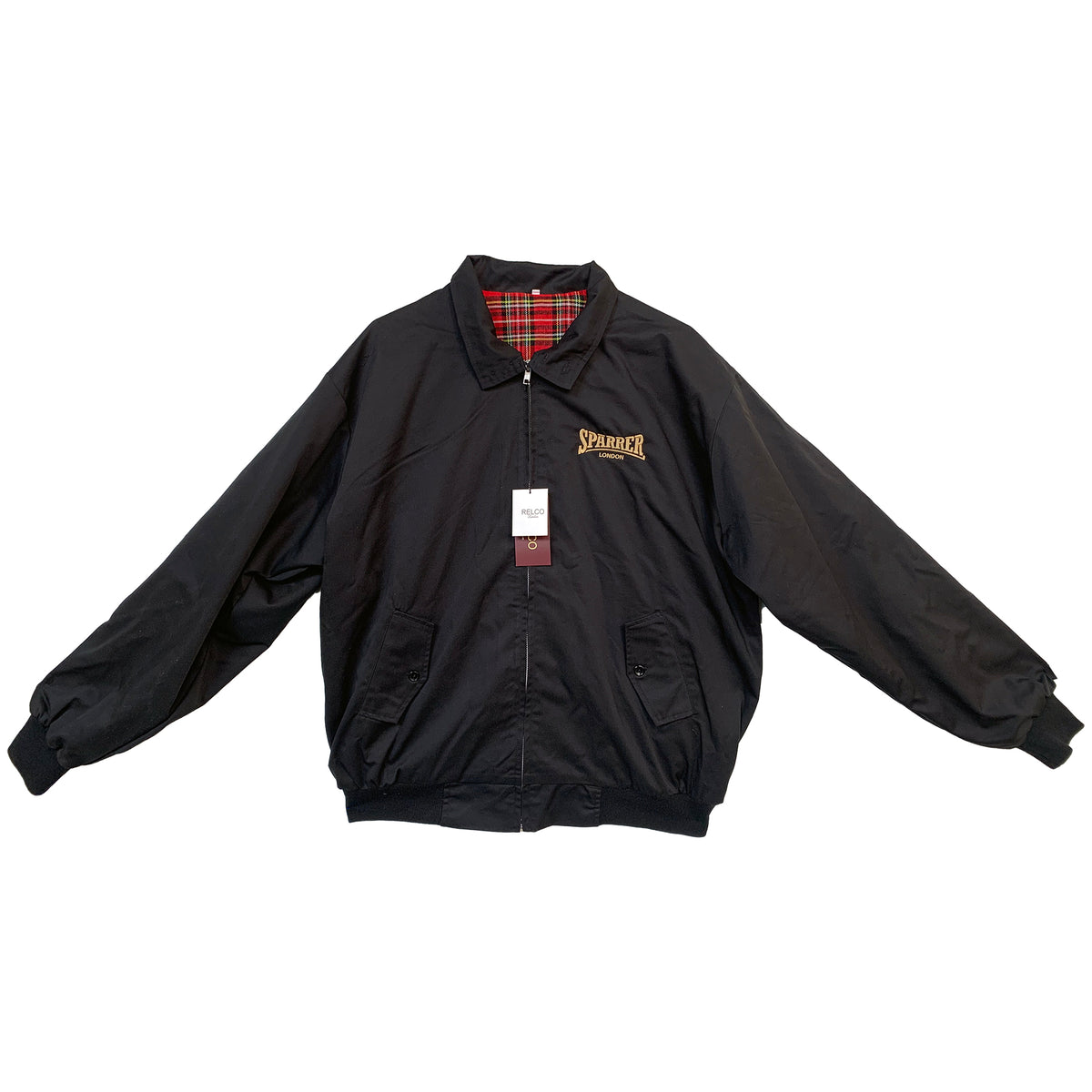 A black Cock Sparrer Harrington jacket with a collar, buttoned cuffs, and red plaid lining. Features a front zipper, two pockets, Cock Sparrer logo on the left chest, and a tag attached to the zipper pull.