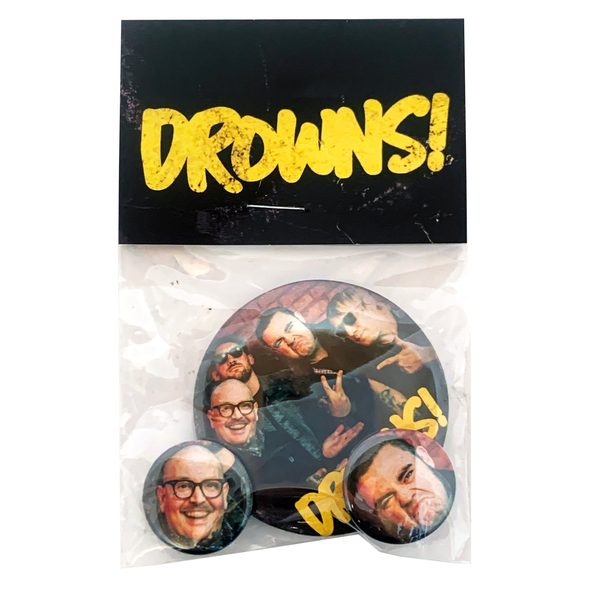 A plastic bag labeled DROWNS! contains The Drowns button pack: three unique 1&quot; buttons with close-up group and individual photos of four men making expressive faces or gestures.
