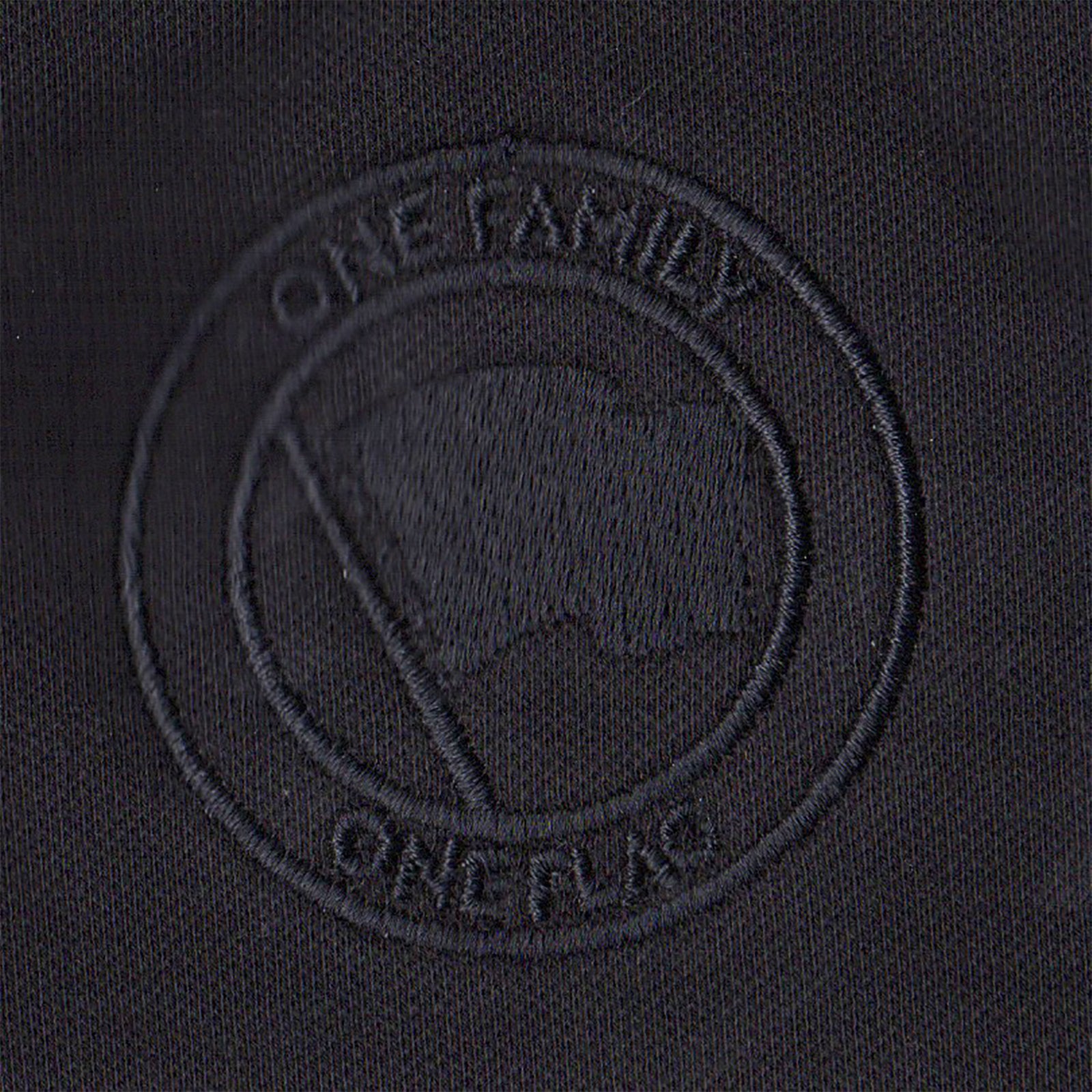 A black fabric patch from Pirates Press Records features an embossed circular emblem with a flag and “ONE FAMILY” above and “ONE FLAG” below, all in black-on-black stitching—ideal for your One Family One Flag polo or gear.