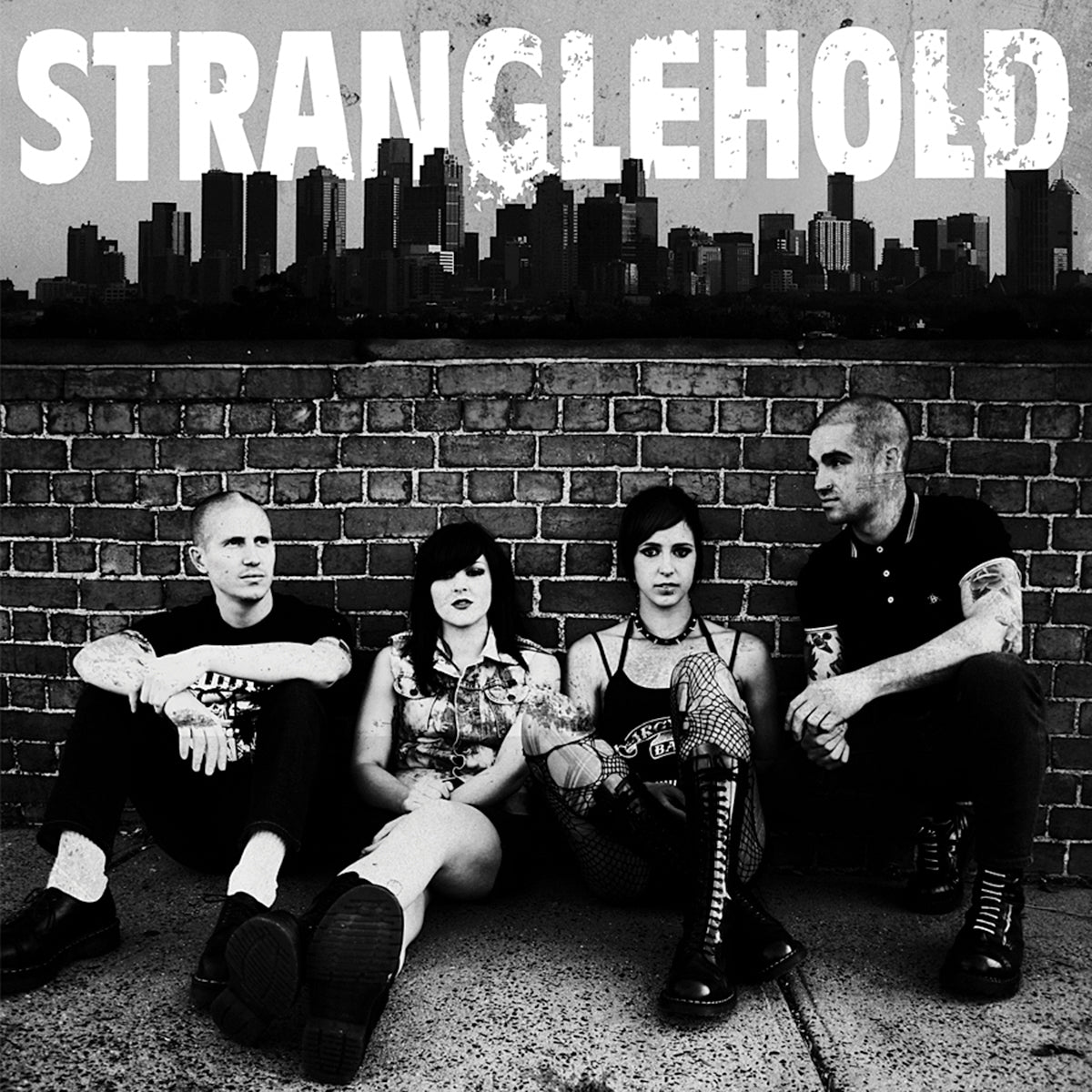 Four people sit against a brick wall with a city skyline behind them. Bold white text above reads Stranglehold, capturing the gritty, urban vibe of this Melbourne punk band. Brand: Stranglehold.