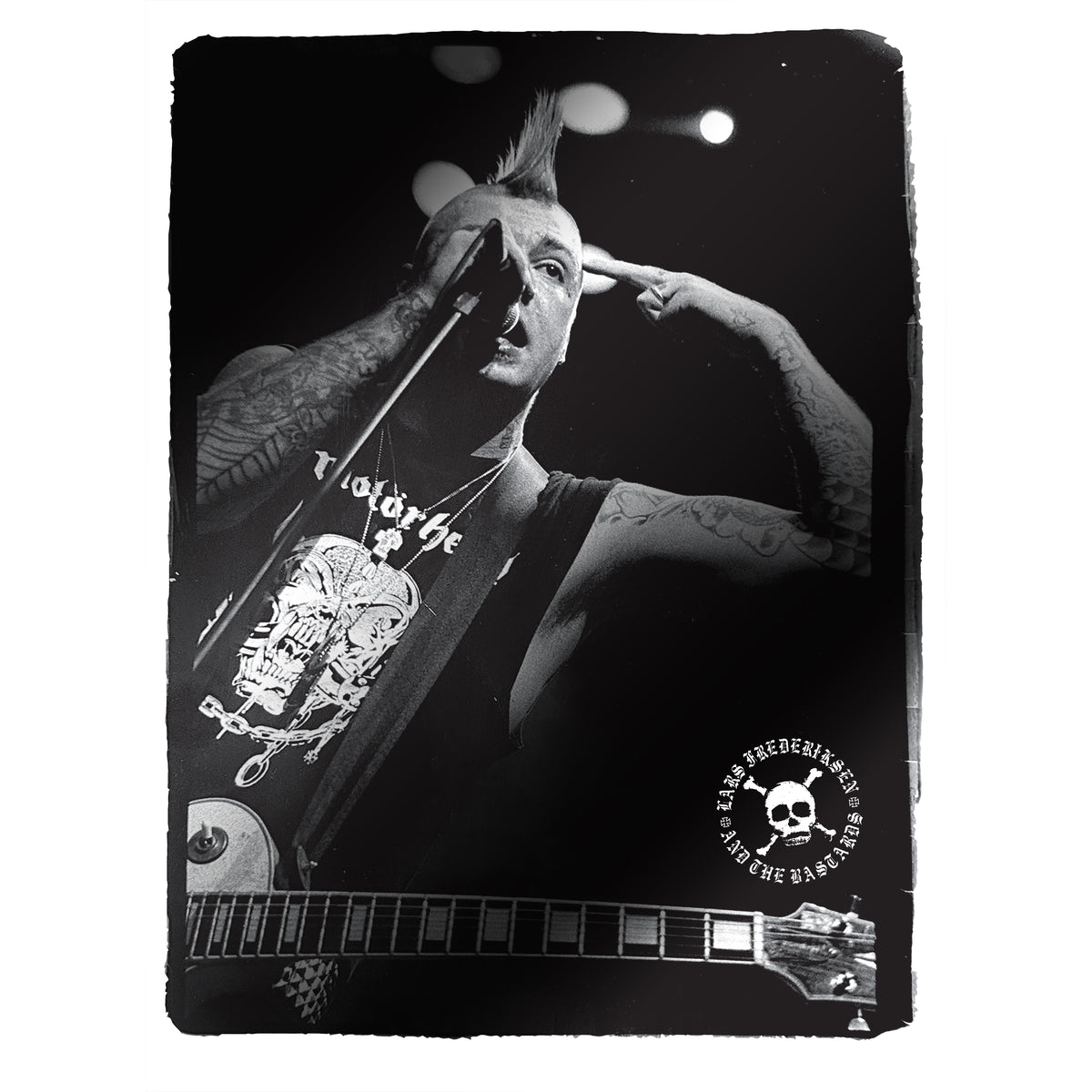Black-and-white photo of a punk musician with a mohawk, tattoos, and a guitar, singing into a microphone and pointing to his head. A skull logo with text appears in the bottom right corner, reminiscent of the iconic imagery from Lars Frederiksen and The Bastards’ self-titled debut album—now available on colored vinyl.