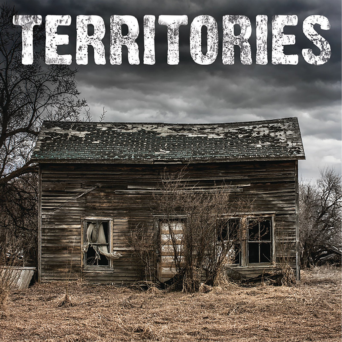 A weathered wooden house with broken windows stands abandoned under a cloudy sky. Large, distressed white text at the top reads “Territories,” referencing the Canadian band’s brand name.
