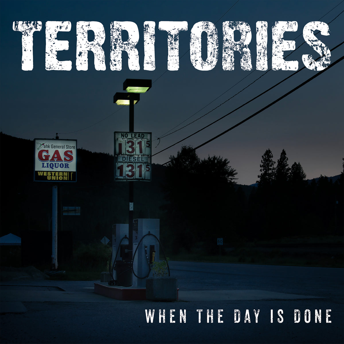 A dimly lit gas station at dusk with a “GAS LIQUOR WESTERN UNION” sign sets the scene, while “TERRITORIES” and “WHEN THE DAY IS DONE” evoke the raw energy of the Territories debut album.