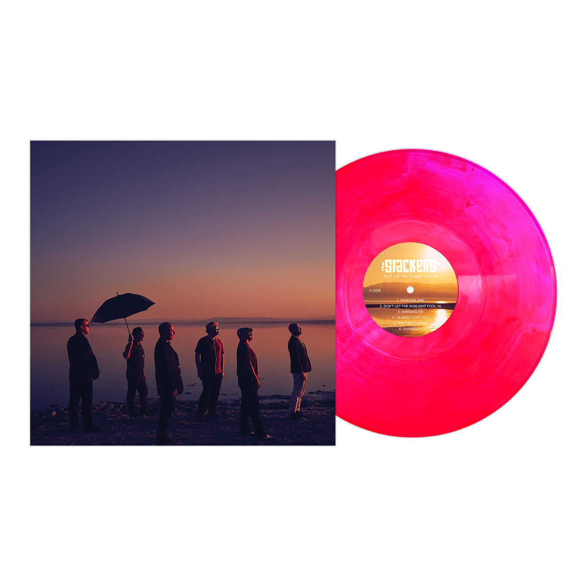 Album cover features six members of The Slackers on a beach at sunset, one with an umbrella. Next to it is a bright pink marbled vinyl from The Slackers, released by Pirates Press Records.