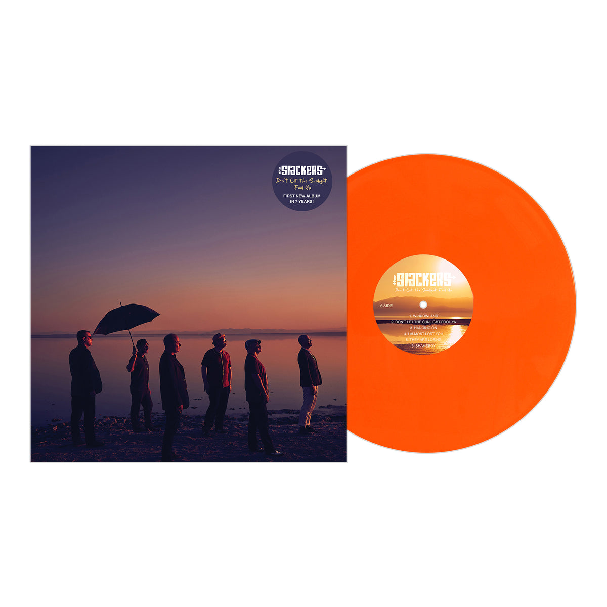 An orange vinyl record by The Slackers rests beside its cover, which shows six people on a sunset shore with purple and orange skies reflected on the water. This album is by The Slackers.
