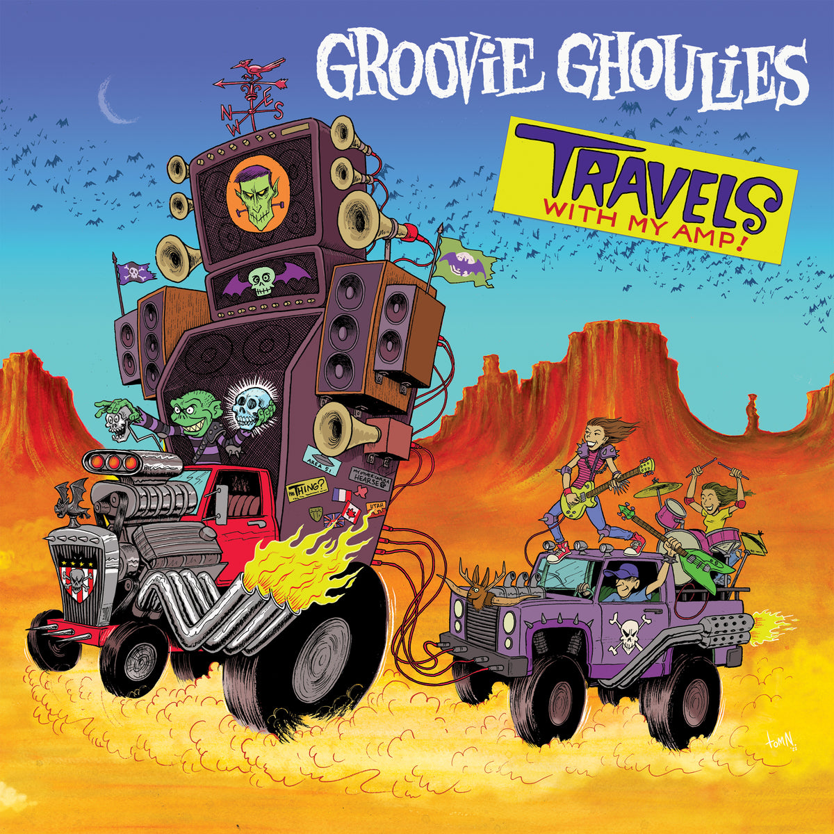 Cartoon monsters from Groovie Ghoulies drive a hot rod loaded with speakers, towing a purple car of guitar-strumming skeletons on a wild musical ride through desert rocks and a vibrant sky. Text: Groovie Ghoulies Travels With My Amp!.