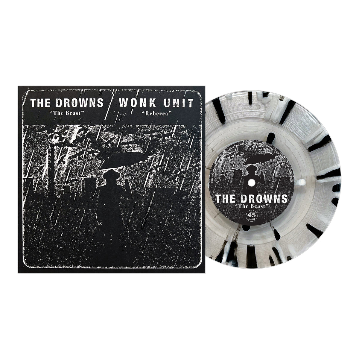 A Pirates Press Records vinyl with black splatter sits beside its cover, showing a silhouetted figure under an umbrella in rain. The cover features punk bands The Drowns and Wonk Unit with songs “The Beast” and “Rebecca.”.