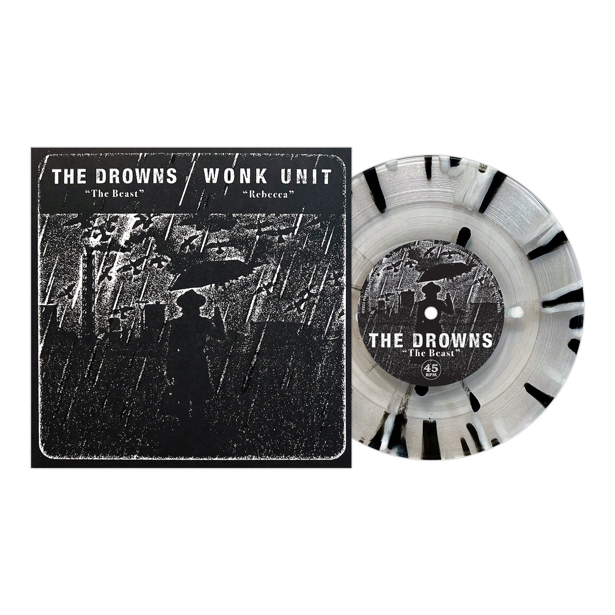 A Pirates Press Records vinyl with black splatter sits beside its cover, showing a silhouetted figure under an umbrella in rain. The cover features punk bands The Drowns and Wonk Unit with songs “The Beast” and “Rebecca.”.