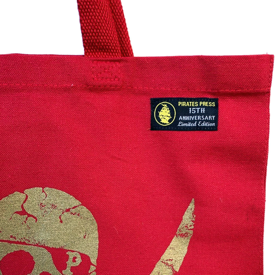 A close-up of a Pirates Press Records canvas shopper bag with a red gusset, gold skull-and-crossbones design, and black label reading “PIRATES PRESS 15TH ANNIVERSARY Limited Edition.”.
