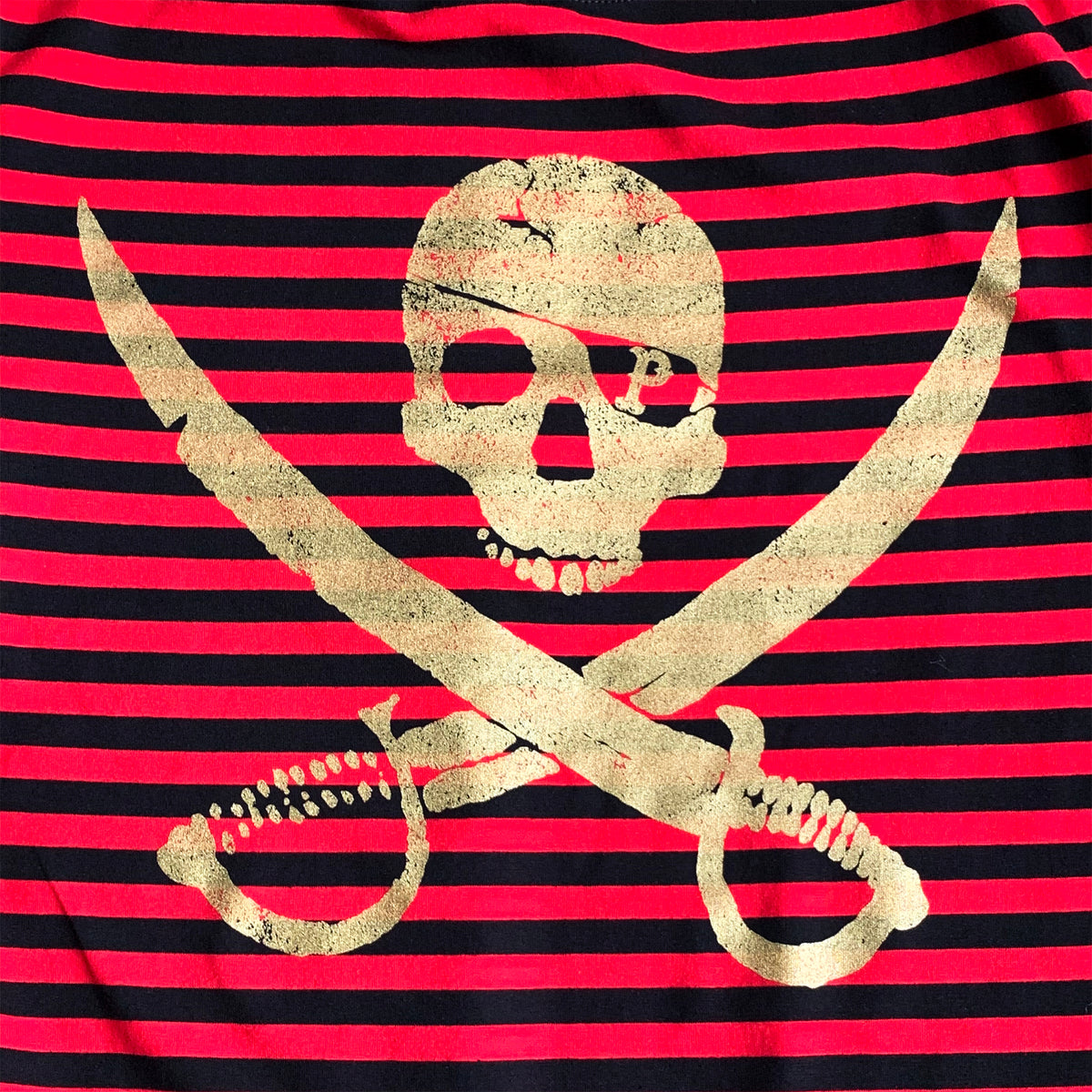 A gold skull above crossed swords is printed on a red and black striped background, creating a pirate-themed shirt from Pirates Press Records.