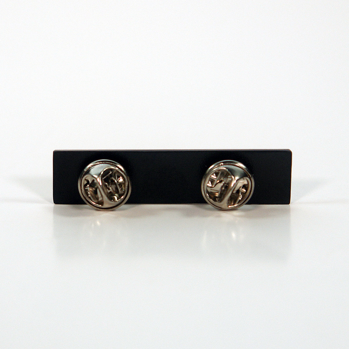 A rectangular black enamel pin by Subhumans, featuring two butterfly clutch fasteners on the back, displayed against a plain white background.