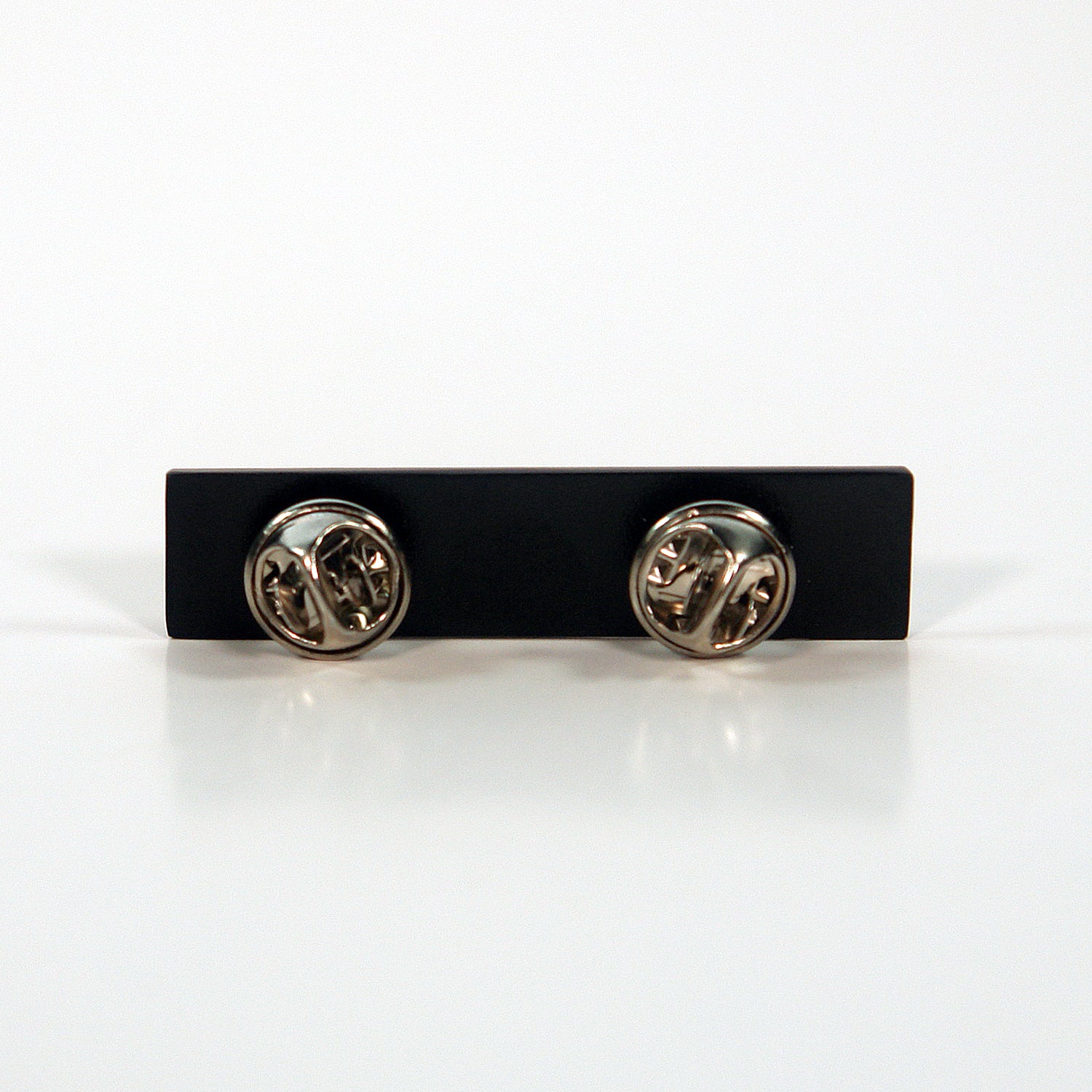 A rectangular black enamel pin by Subhumans, featuring two butterfly clutch fasteners on the back, displayed against a plain white background.