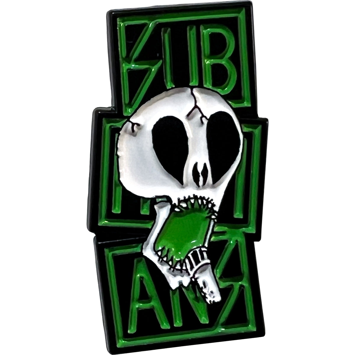 The Subhumans enamel pin features a white skull with black eye sockets and nose biting a green object, set against bold green and black block letters spelling Subhumans.