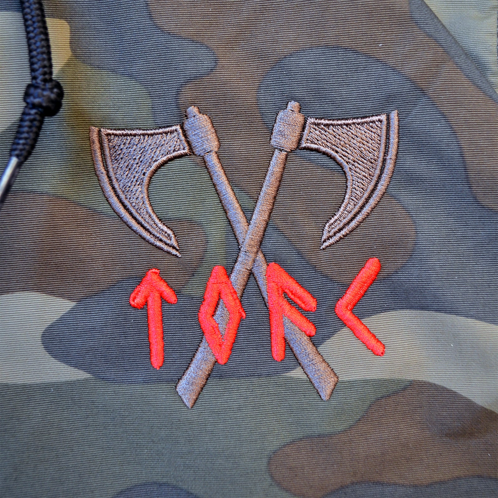A camouflage windbreaker from The Old Firm Casuals features two embroidered crossed axes and red runic letters spelling TORC—ideal for fans of the Old Firm Casuals style.