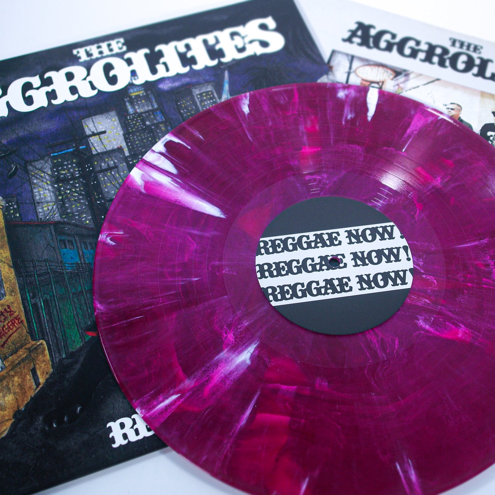 A Joker Marble Reggae vinyl labeled "Reggae Now!" by The Aggrolites rests partially on its album cover, with another "Reggae Now!" title seen in the background.