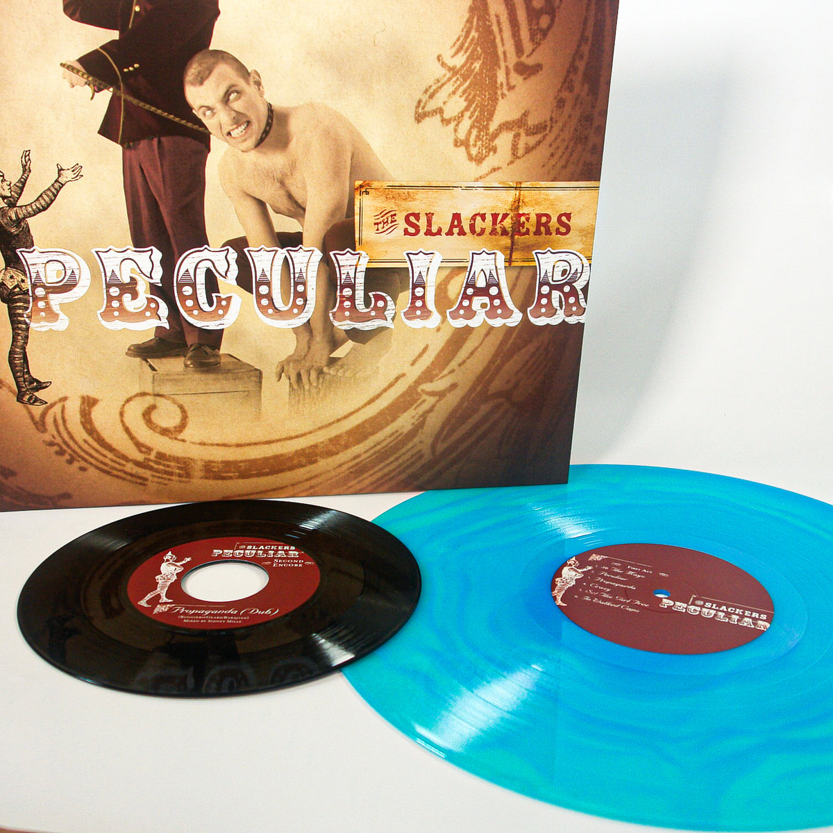 Two Vinyl LPs—one black, one Electric Blue—are displayed in front of The Slackers’ Peculiar album cover, which features vintage circus-style artwork and lettering.