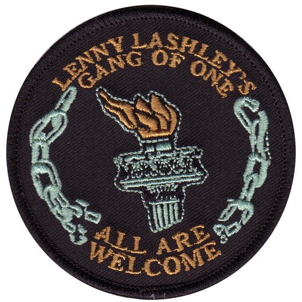 This circular embroidered patch from Lenny Lashley&#39;s Gang Of One features a central torch, broken chain border, and the phrases &quot;Lenny Lashley&#39;s Gang Of One&quot; above and &quot;All Are Welcome&quot; below.