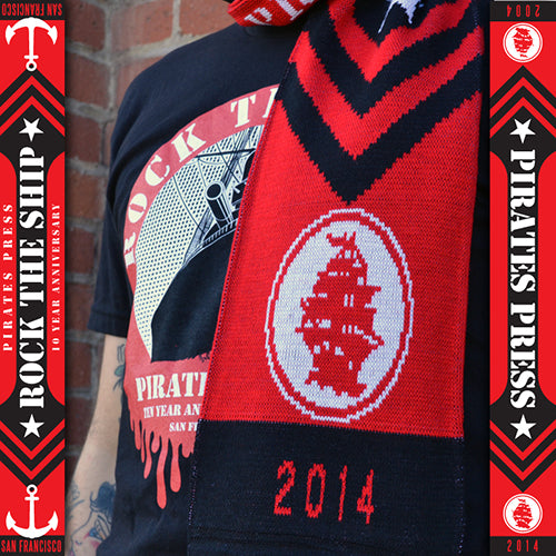 A person wearing a black t-shirt with a ship graphic and a Pirates Press Records scarf featuring a white ship, &quot;2014,&quot; and borders reading &quot;Rock the Ship,&quot; &quot;PP10,&quot; &quot;Pirates Press Records,&quot; and &quot;10 Year Anniversary.