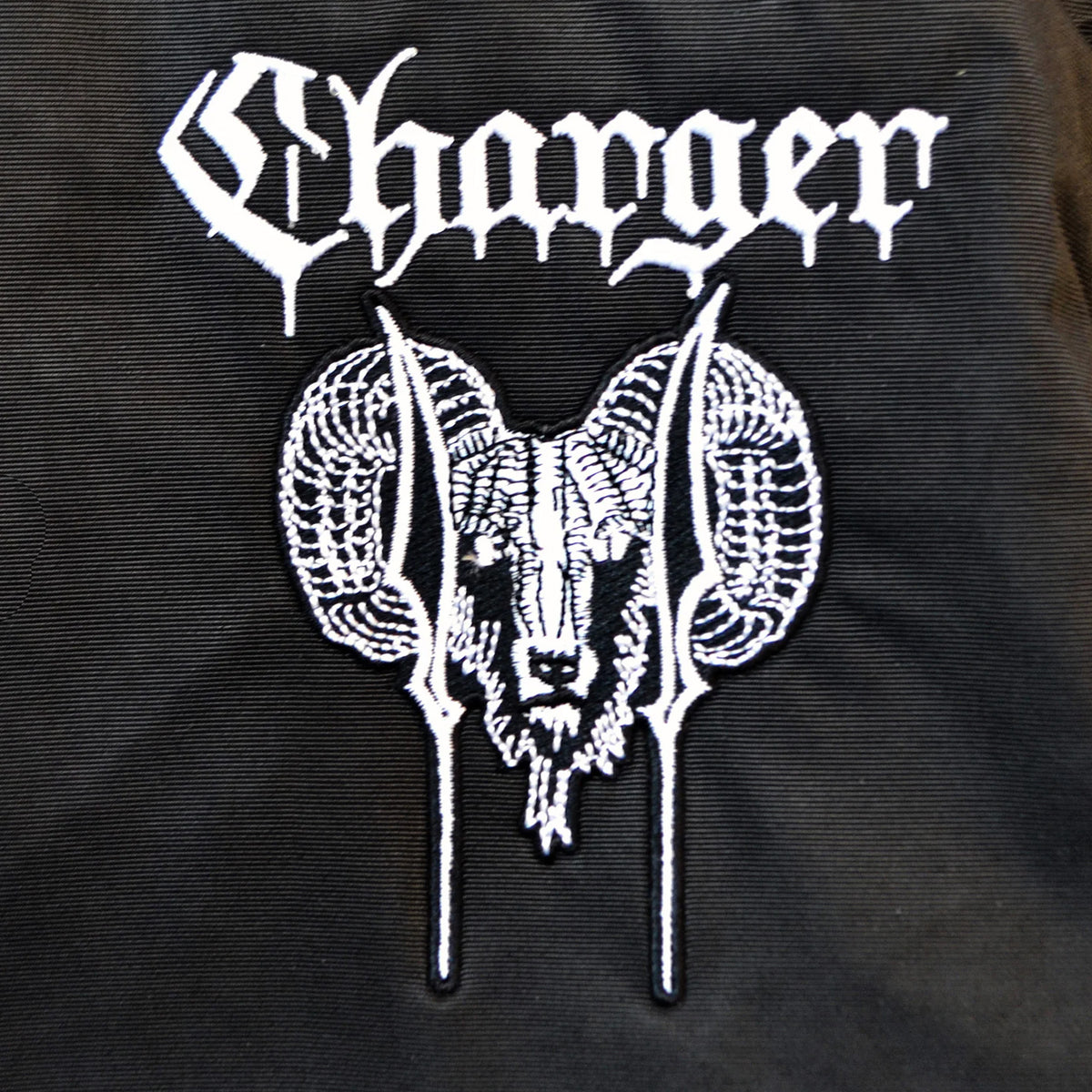 White stylized Charger text above an embroidered ram’s head with curled horns stands out on black fabric in this bold, gothic design featured on the Charger windbreaker weatherproof hooded anorak.
