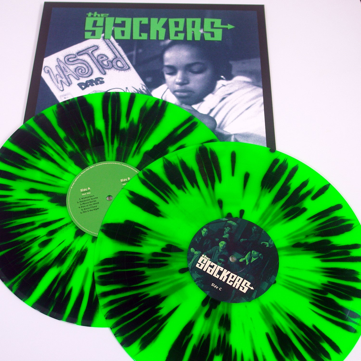 Two vivid green vinyl records with black splatter from The Slackers are displayed before their grayscale record sleeve, which features a photo and the bands name. Their ska, reggae, and rocksteady sound is reflected in the design.