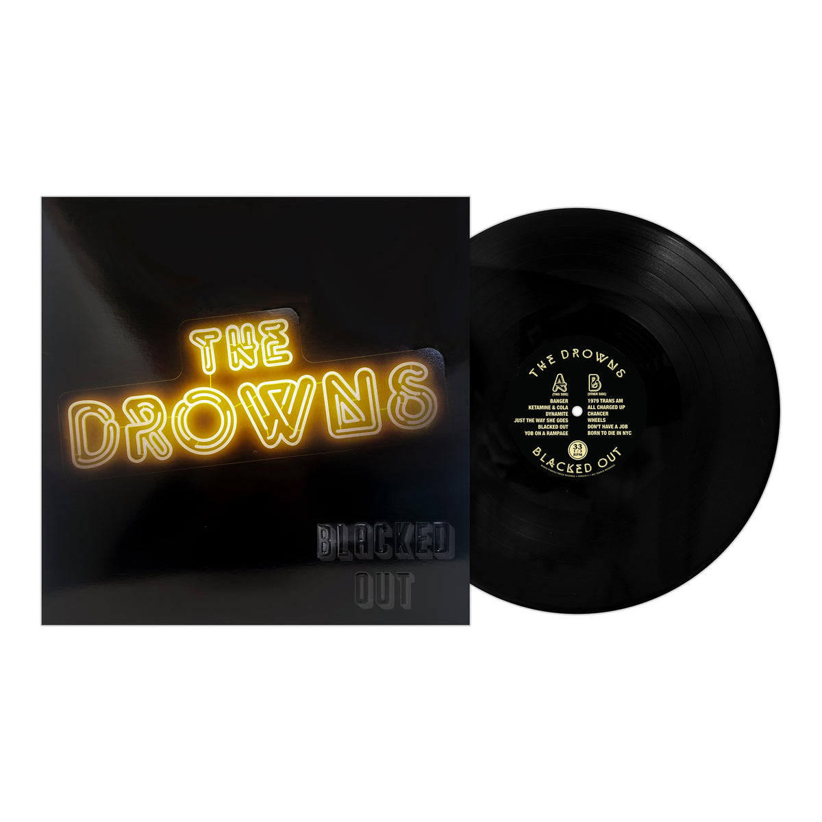 A black vinyl record by The Drowns is partly visible next to its sleeve, which displays the band’s name in yellow neon-style letters and the album title Blacked Out in black embossed text.