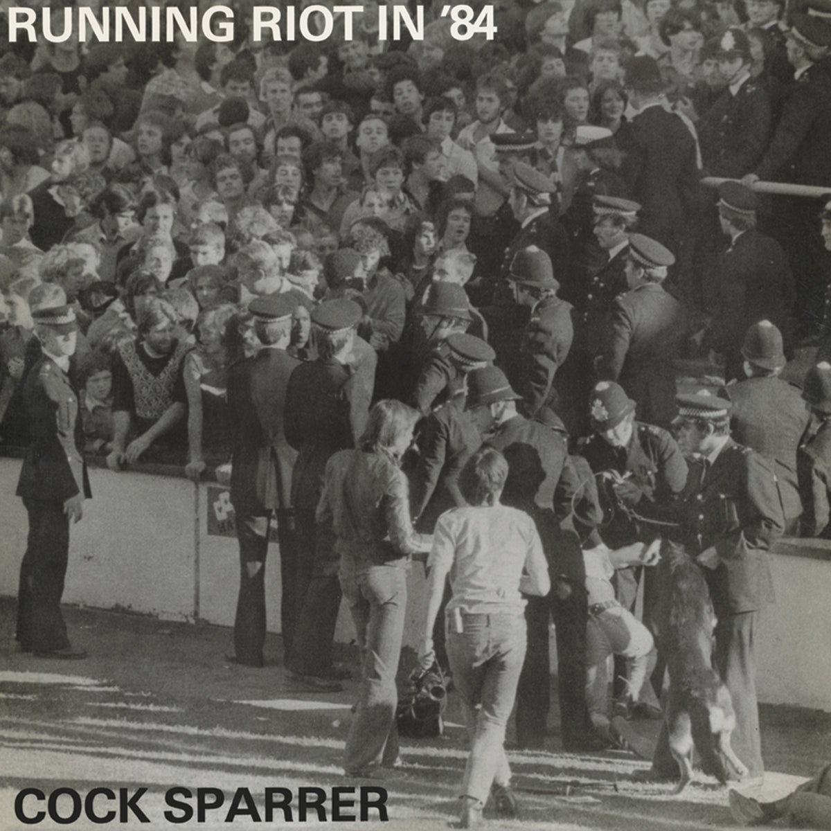 Black-and-white photo shows police and a dog facing stadium fans, with RUNNING RIOT IN ’84 at the top and Cock Sparrer 50th anniversary at the bottom. Brand: Cock Sparrer.